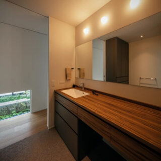 １階、洗面脱衣室。大きな鏡とカウンターが使いやすい。廊下に出ると光庭（画像左奥）の緑が目に入る

