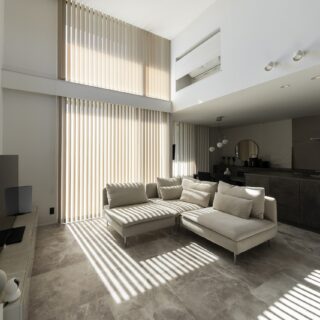 LDK。クライアントの「ホテルライクな室内空間」という要望に応え、冷蔵庫や電子レンジ、エアコンなどの家電をなるべく目立たない設計に。床は大理石調のフロアタイルを採用