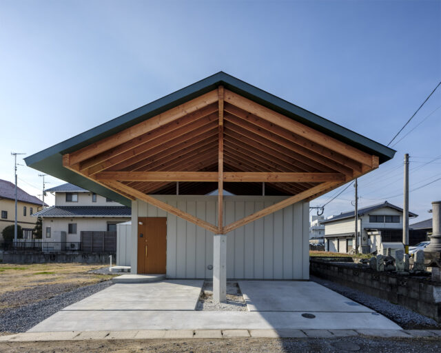 窓がない外観（正面）。切妻の大屋根が最大の特徴だ。柱を中央にすることで、雨で木の柱が傷まず、車の出し入れが容易になった。玄関ドアは外壁の縦のラインに合うように製作されている。木の梁に屋根が乗っているようなデザインにするため、軒の裏側も屋根と同じ色に塗装した
