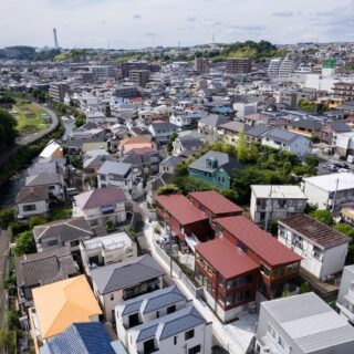 物件の空から眺める。赤茶色の4棟の建物が「栗の木テラス」。帷子川へ続く段丘地に立地した、高低差のある地形を活かした計画だということがよく分かる。周辺環境にも違和感なく調和している