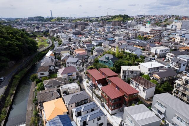 物件の空から眺める。赤茶色の4棟の建物が「栗の木テラス」。帷子川へ続く段丘地に立地した、高低差のある地形を活かした計画だということがよく分かる。周辺環境にも違和感なく調和している